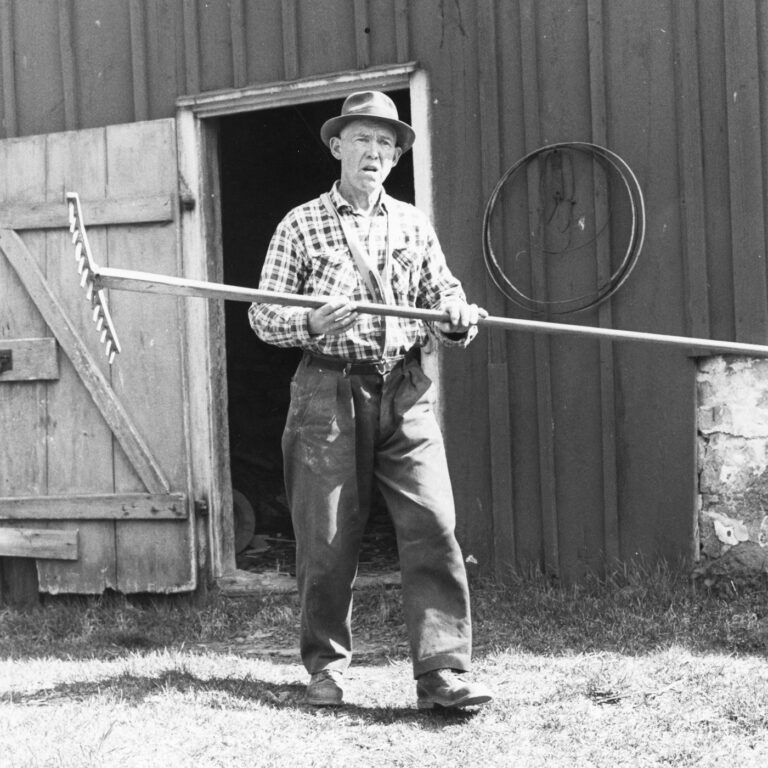 Anders Hallberg på Skattegården i Gärdhem har häftat räfsan av trä inför höbärgning. Okänt fotograferingsår. Troligen 1970-talet, eller tidigt 1980-tal. Fotograf: Erling Svensson. Bildkälla: Innovatums bildarkiv.